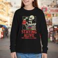Staying Alive One Book At A Time Skeleton Reading Librarian Youth Long Sleeve Tee