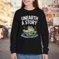 Unearth a Story Frog Reading a Book Summer 2026 Youth Long Sleeve Tee Unearth a Story Frog Reading a Book Summer 2026 Youth Long Sleeve Tee