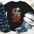 Staying Alive One Book At A Time Skeleton Reading Librarian Youth Long Sleeve Tee