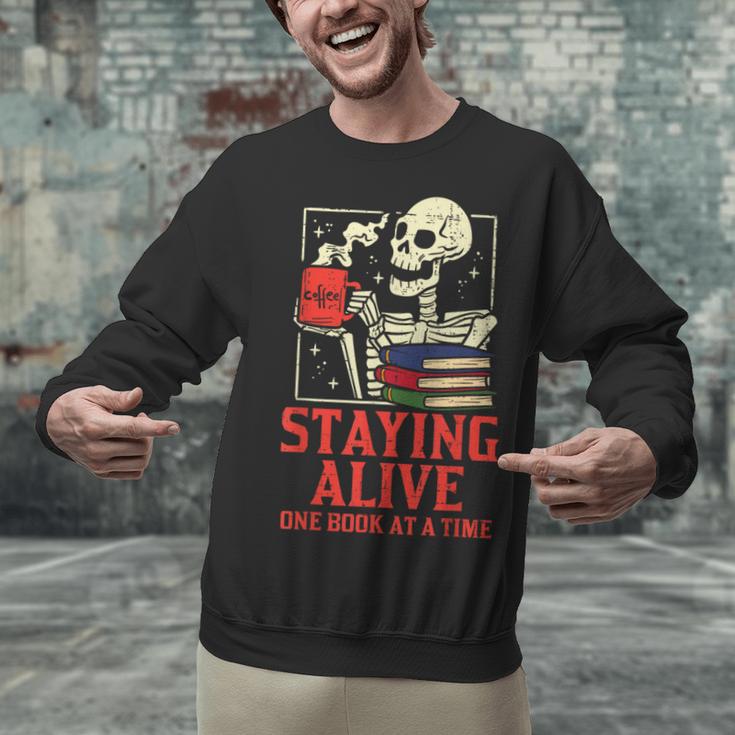 Staying Alive One Book At A Time Skeleton Reading Librarian Unisex Sweatshirt Staying Alive One Book At A Time Skeleton Reading Librarian Unisex Sweatshirt