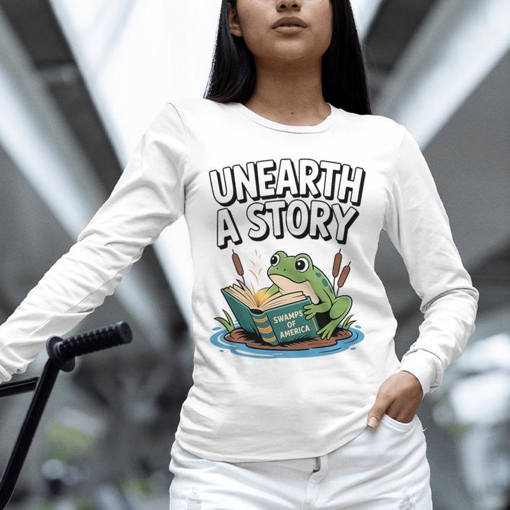 Unearth a Story Frog Reading a Book Summer 2026 Premium Tri-Blend Unisex Long Sleeve T-Shirt Unearth a Story Frog Reading a Book Summer 2026 Premium Tri-Blend Unisex Long Sleeve T-Shirt