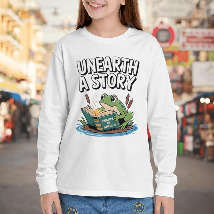 Unearth a Story Frog Reading a Book Summer 2026 Premium Tri-Blend Youth Long Sleeve Tee Unearth a Story Frog Reading a Book Summer 2026 Premium Tri-Blend Youth Long Sleeve Tee