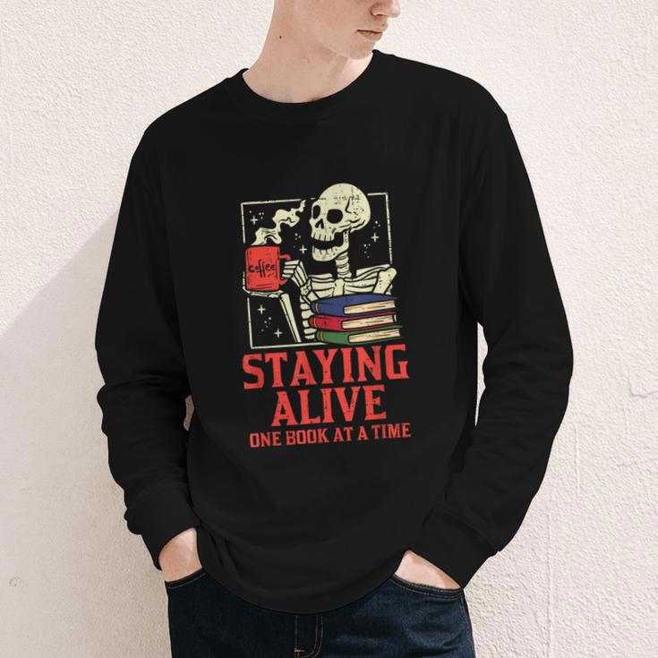 Staying Alive One Book At A Time Skeleton Reading Librarian Youth Long Sleeve Tee