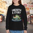 Unearth a Story Frog Reading a Book Summer 2026 Youth Long Sleeve Tee Unearth a Story Frog Reading a Book Summer 2026 Youth Long Sleeve Tee